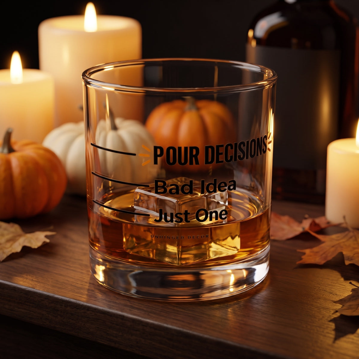 Pour Decision rocks glass 'Just One / Bad Idea' with whiskey on a big ice cube on a fall home bar with candles and pumpkins, Unhinged Decor